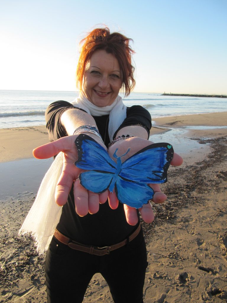 escritora Luz Ros con dibujo mariposa azul en las manos